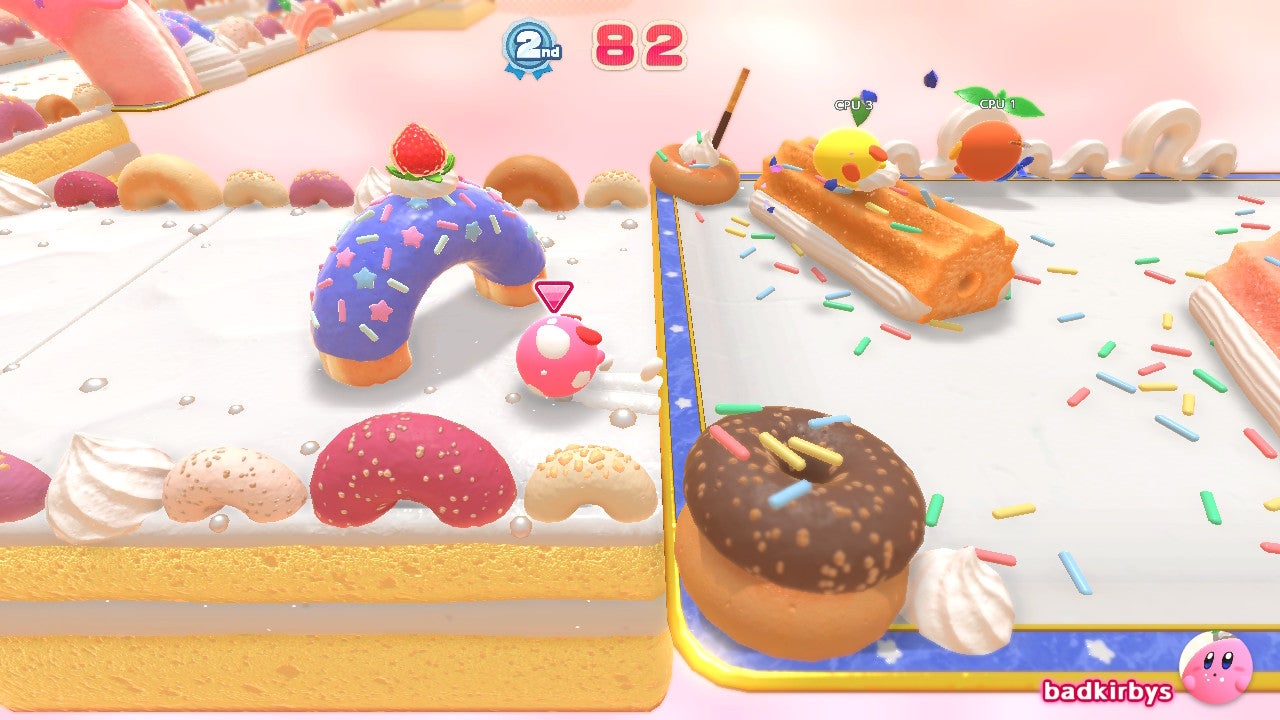 Drie verschillende kleuren Kirby's race op een parcours met donutthema in Kirby's Dream Buffet
