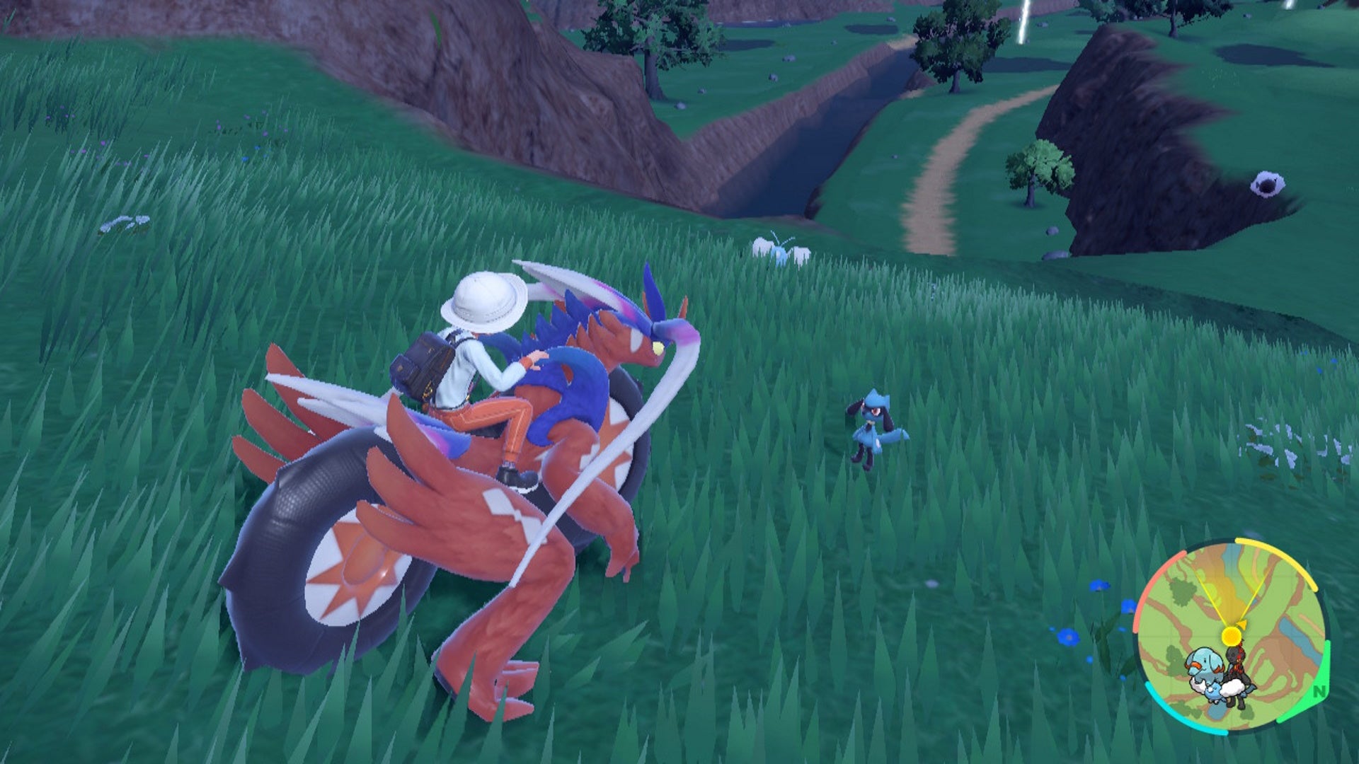How to get Riolu in Scarlet and Violet: An anime child sitting on a large red lizard in a field is looking at a small blue and black creature with floppy ears